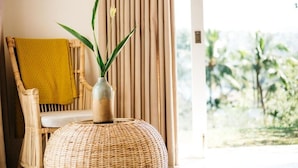 A wicker chair with a yellow towel, a wicker ottoman, and a vase with a plant. - Rukgala Retreat (Digana, Kandy)