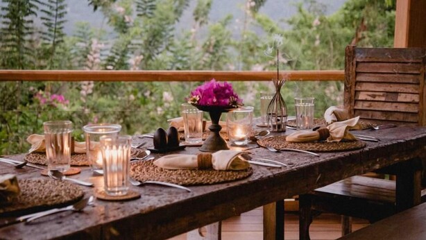 A wooden dining table set with candles, glasses, and a centerpiece. - Rukgala Retreat (Digana, Kandy)