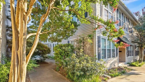 A two-story house with a front porch, a pathway leading to the entrance, and a large tree on the left. - Walkable Downtown Stay | Pet-Friendly & Spacious (Raleigh)
