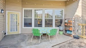 A covered patio with a table and chairs, a door, and a window with blinds. - Walkable Downtown Stay | Pet-Friendly & Spacious (Raleigh)