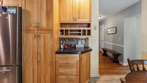 Une cuisine avec des meubles en bois, un réfrigérateur en acier inoxydable et un plan de travail noir.