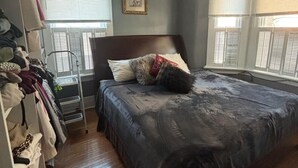 Ein Schlafzimmer mit einem großen Bett, einem Kleiderschrank und einem Fenster mit Jalousien.