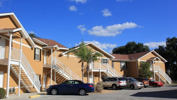 A row of two-story motel buildings with balconies and a parking lot.