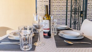 Una tavola apparecchiata con bicchieri da vino, una bottiglia e piatti, con una parete decorata di piastrelle sullo sfondo.