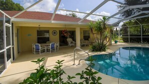 A covered outdoor swimming pool area with a patio, chairs, and a small table. - 3 Bedroom & 2 bath with private pool (Hernando)