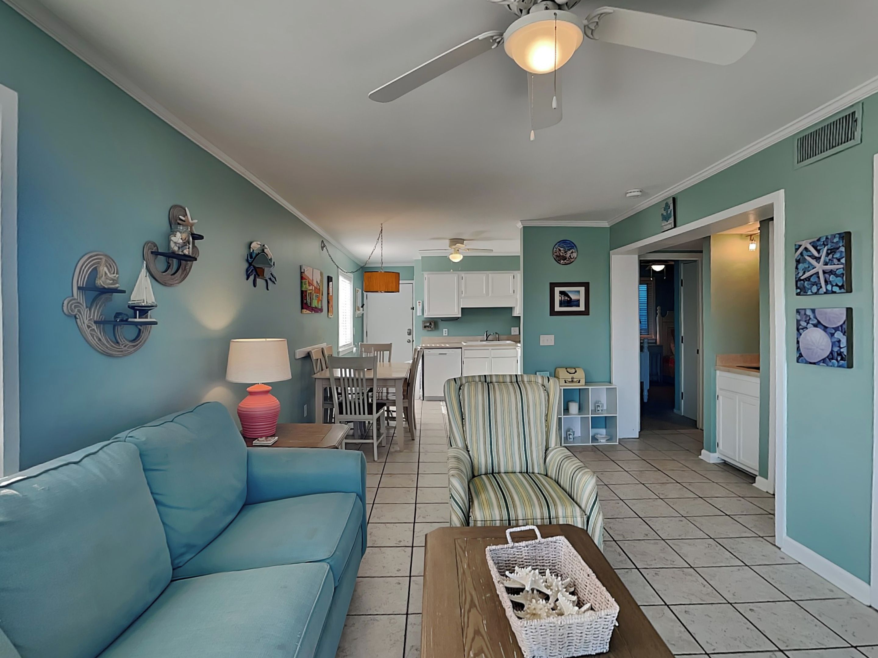 A living room with a blue sofa, a striped armchair, and a coffee table with a basket.