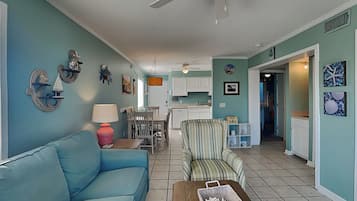 A living room with a blue sofa, a striped armchair, and a coffee table with a basket.