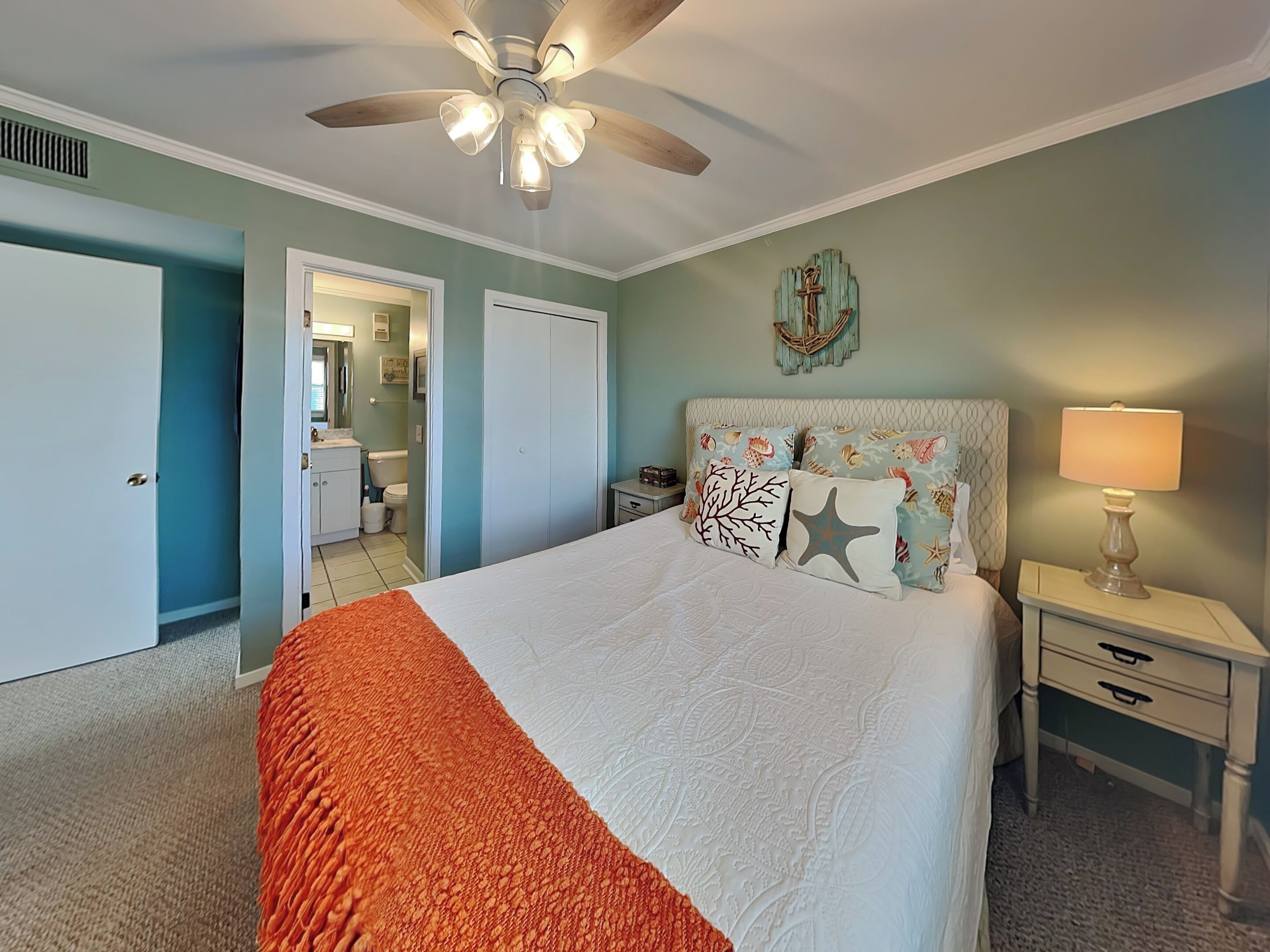 A bedroom with a bed, nightstands, a ceiling fan, and a wall-mounted cross.