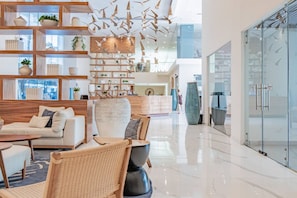 Een moderne hotellobby met een receptiebalie, een zithoek en decoratieve elementen zoals hangende mobielen.