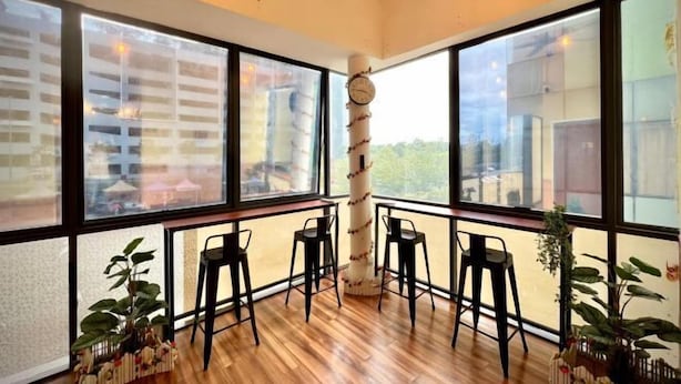 Un interno moderno con ampie finestre, pavimento in legno e sgabelli da bar.