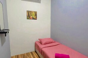 Een kleine kamer met een bed, een wandplank en een schilderij.