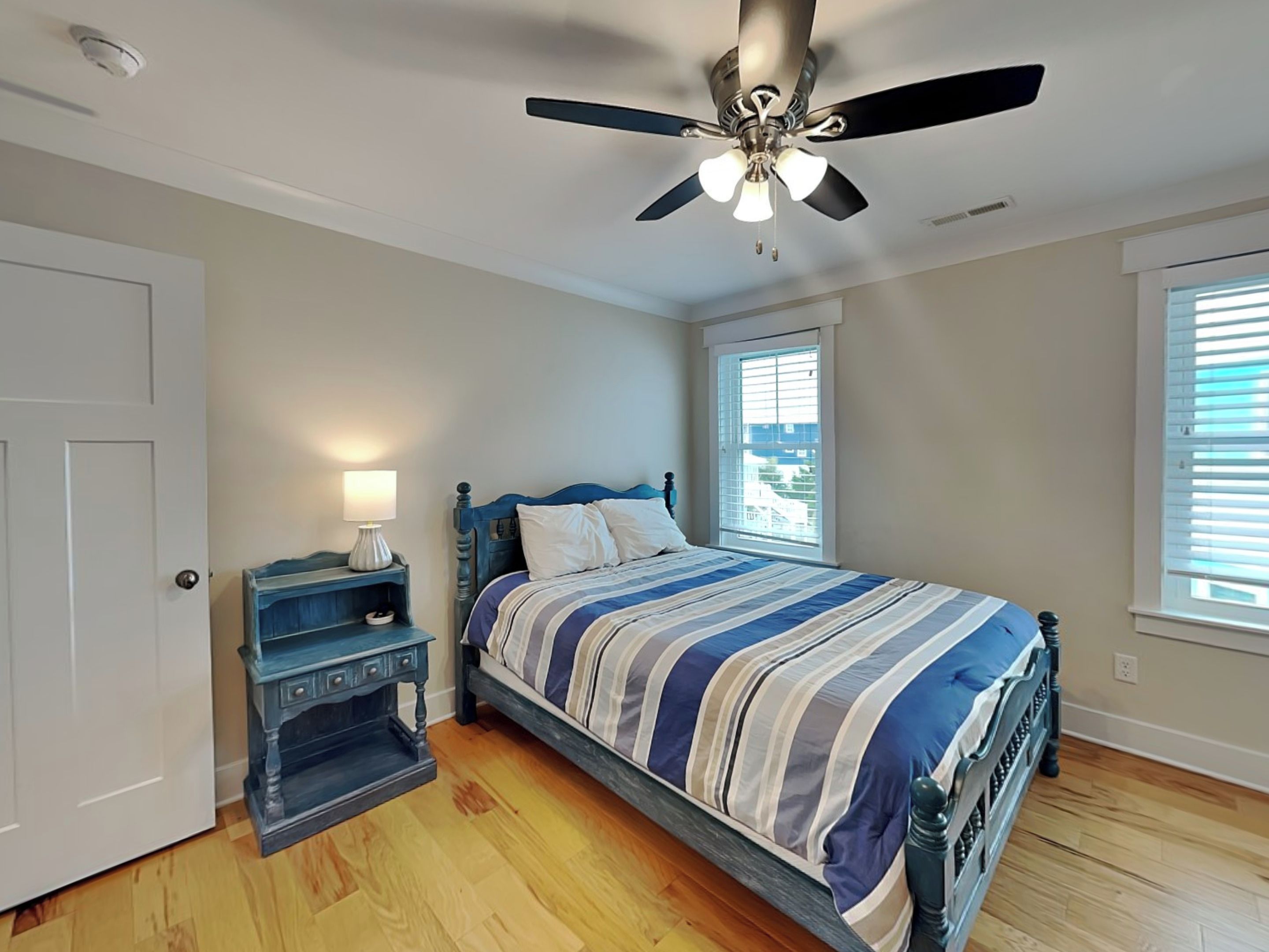 A bedroom with a bed, a nightstand, a ceiling fan, and a window.