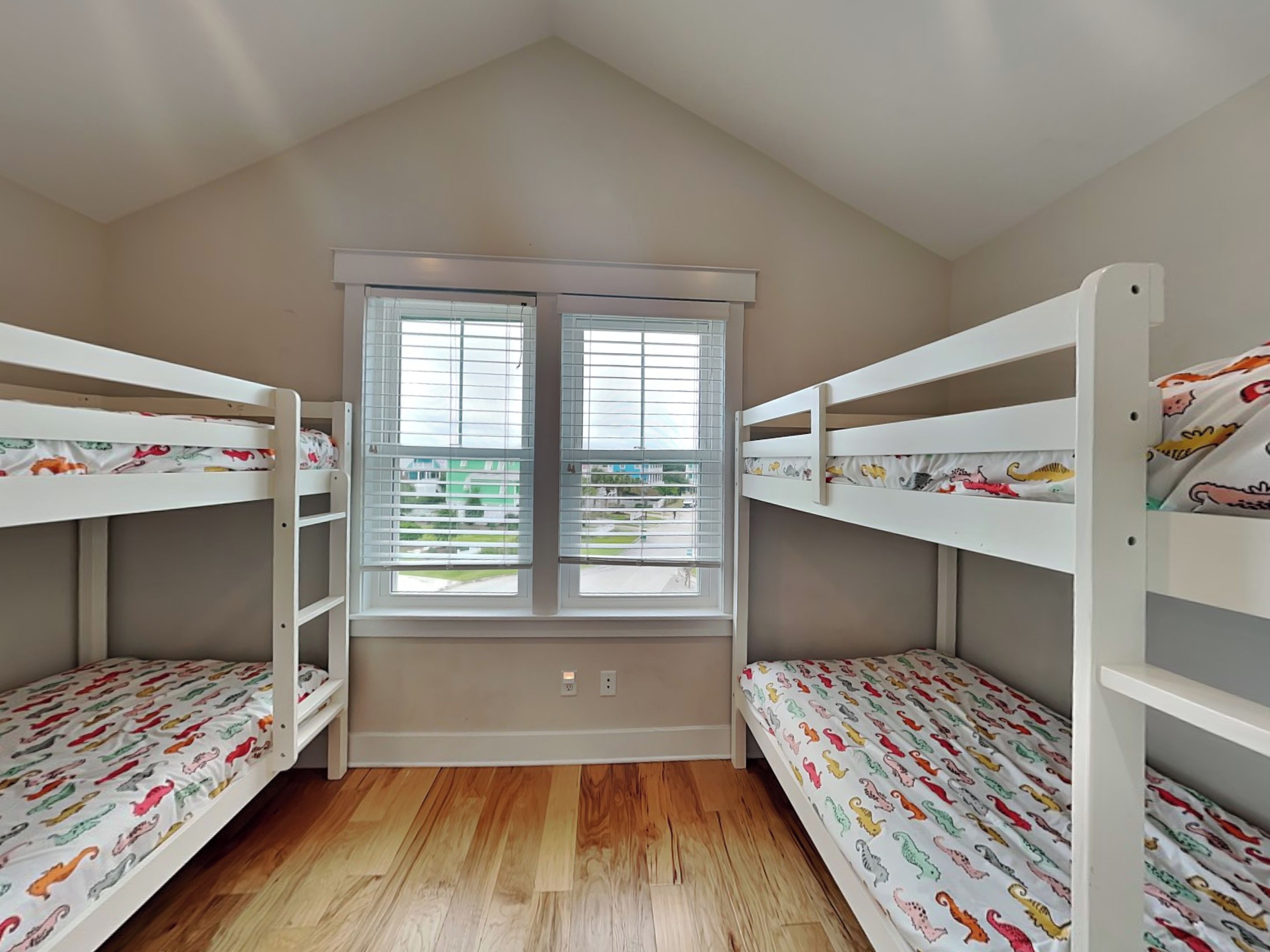 Une chambre avec deux lits superposés, une fenêtre avec des stores et une vue sur l’extérieur.
