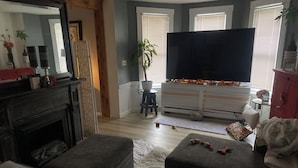 Ett vardagsrum med en öppen spis, en tv och en soffa.