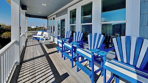A covered porch with blue Adirondack chairs and a wooden deck. - Good Tide-ings (Sneads Ferry)