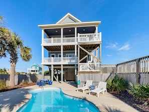 A multi-story beachfront house with a pool, deck chairs, and a wooden fence. - Good Tide-ings (Sneads Ferry)