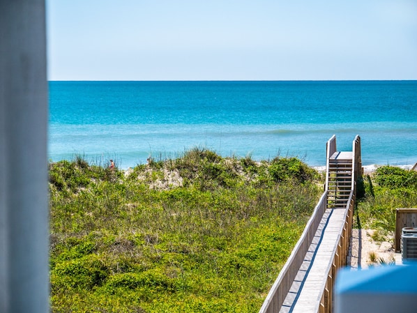 A wooden boardwalk leading to a beach with clear blue water. - Good Tide-ings (Sneads Ferry)
