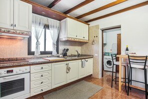 Eine Küche mit weißen Schränken, einem eingebauten Backofen, einer Spüle und einem Essbereich mit zwei Stühlen.