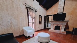 Una sala de estar con chimenea, un sillón blanco, un sofá negro y una alfombra.