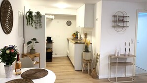 Ett modernt kök med vita skåp, en träbänkskiva och en matplats med ett vitt bord och stolar.