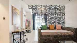 A modern living room with a sofa, a dining table, and a decorative mirror. - Stylish Downtown Studio w/ Pool & Gym Access (Dubai)