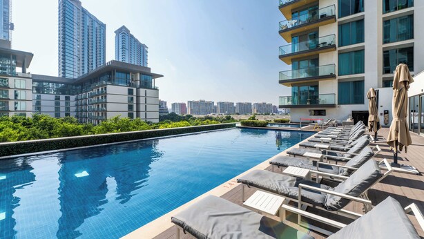 A rooftop pool with lounge chairs and a view of high-rise buildings. - Stylish Downtown Studio w/ Pool & Gym Access (Dubai)