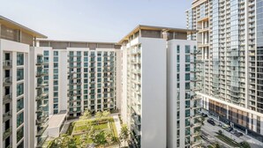A high-rise residential building with multiple balconies and a central courtyard. - Stylish Downtown Studio w/ Pool & Gym Access (Dubai)