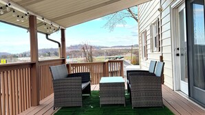 A covered patio with wicker furniture, a table, and a view of the landscape. - Cozy house in Bridgeport WV - 5 Bedrooms (Bridgeport)
