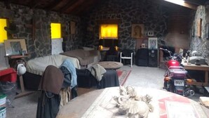 Um quarto rústico com paredes de pedra, uma cama, uma mesa e uma motocicleta.