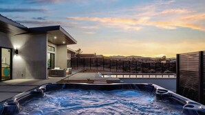 Et moderne udeområde med jacuzzi og udsigt over byen i solnedgang.
