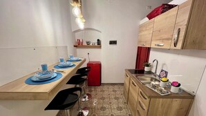 Eine kleine Küche mit Holzarbeitsplatte, einem roten Kühlschrank, einer Spüle und einem Essbereich mit blauen Tellern und Stühlen.