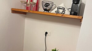 Eine kleine Küchenzeile mit einem roten Kühlschrank, einer Holzauslage mit Küchenutensilien und einer Steckdose.