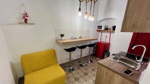 Eine kompakte Küche mit gelbem Stuhl, einer kleinen Bar und einer Spüle sowie einer Mikrowelle.
