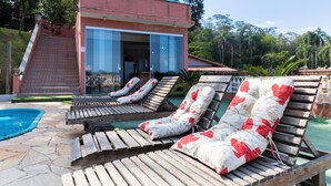 A pool area with wooden loungers and a building with large windows.