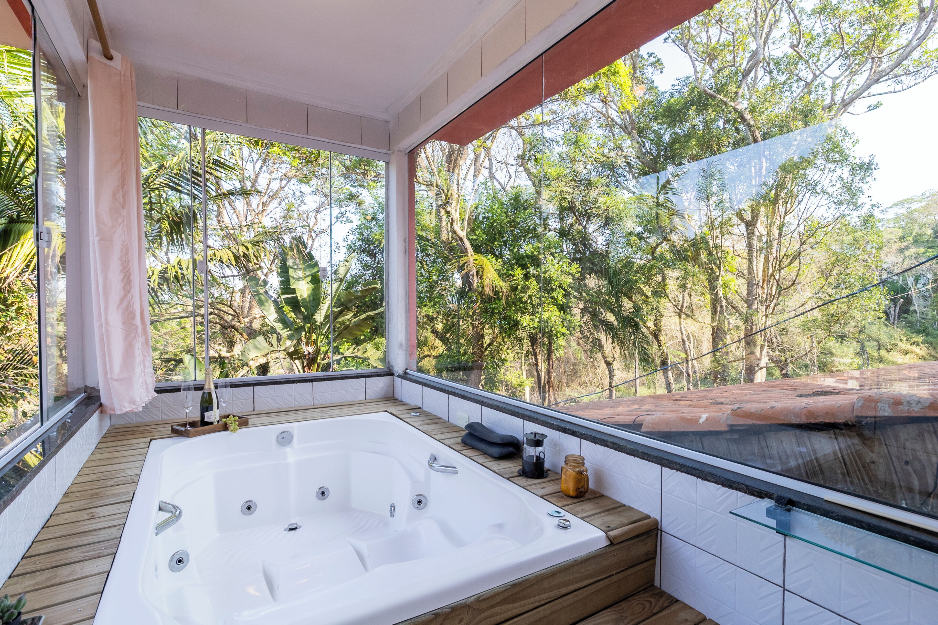 A private balcony with a hot tub, wooden flooring, and a glass railing.