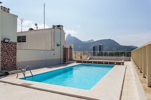 Ein Dachpool mit Bergblick, umgeben von Gebäuden mit Kachelwänden und einem Metallgeländer.