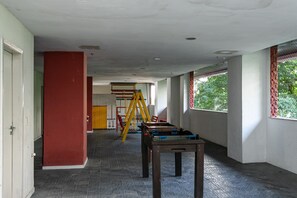 Un couloir avec une table de billard, une structure d’escalade et une porte donnant sur une autre pièce.
