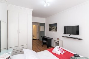 Une chambre d’hôtel équipée d’un lit, d’un bureau, d’une chaise, d’une télévision et d’une armoire.
