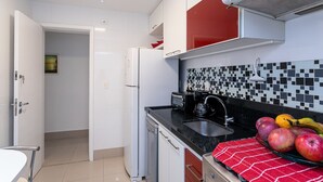 A modern kitchen with white and red cabinets, a black countertop, and a tiled backsplash. - Sunset Urca - Conforto e lazer (Rio de Janeiro)