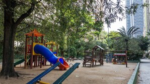 Ein Spielplatz mit Rutsche, Wippe und Klettergerüsten.