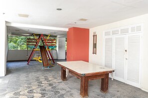 Une pièce avec une grande table en bois, un mur d’accent rouge et une fenêtre donnant sur un paysage verdoyant.