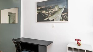Ein Zimmer mit dunklem Holztisch, einem Stuhl, einem weißen Regal und einem gerahmten Stadtbild an der Wand.