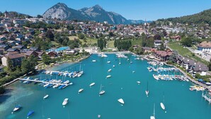 A marina with boats docked, surrounded by residential buildings and mountains in the background. - Lakefront Apartment in Spiez Bay (Spiez)