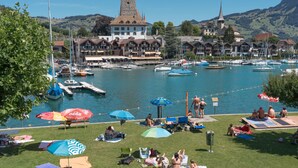 A marina with boats, a tower, and a town with traditional architecture. - Lakefront Apartment in Spiez Bay (Spiez)