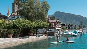 A waterfront with a historic building, a church spire, and boats. - Lakefront Apartment in Spiez Bay (Spiez)