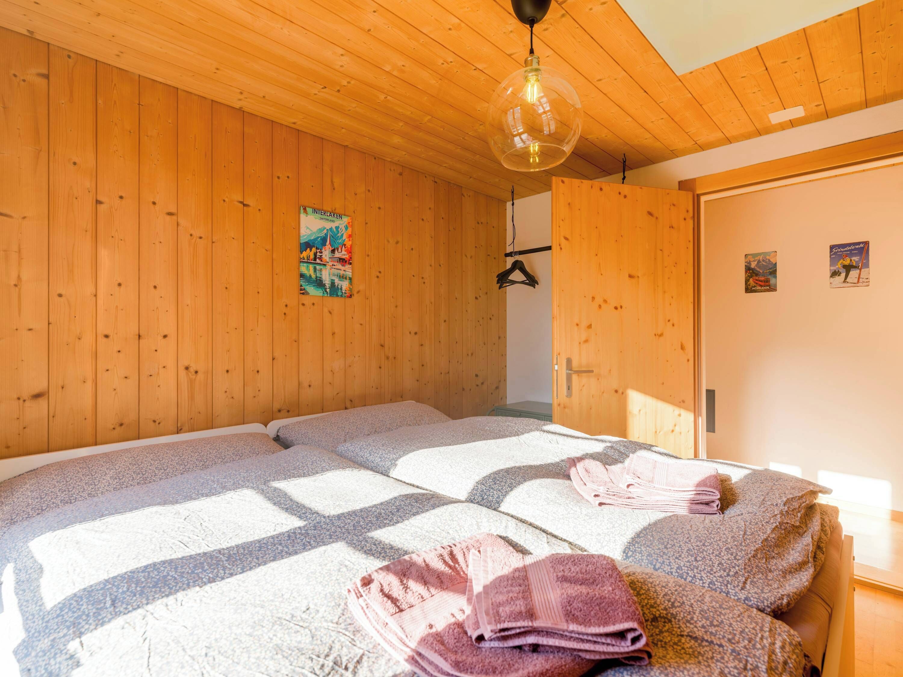 Ein Zimmer mit Holzwänden und einem Bett mit gemustertem Überwurf.