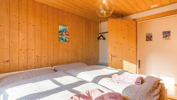 Ein Zimmer mit Holzwänden und einem Bett mit gemustertem Überwurf.