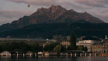 Un lago con una montaña al fondo, un edificio con una bandera y un globo aerostático.