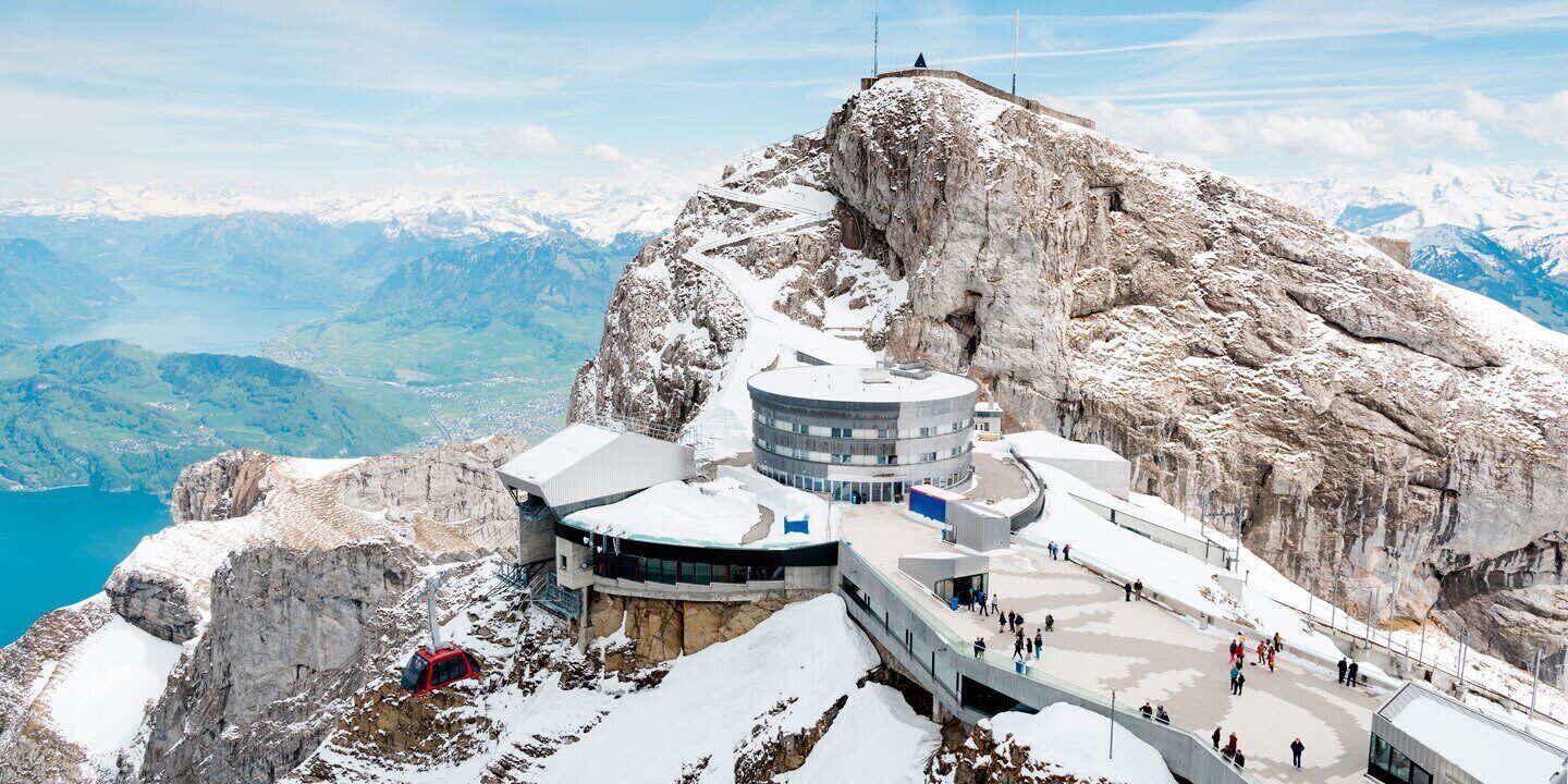 Un rifugio alpino con un edificio circolare, una seggiovia e vista su un lago e le montagne.