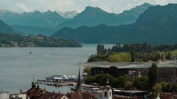 A lakeside town with a church, a dock with boats, and mountains in the background.